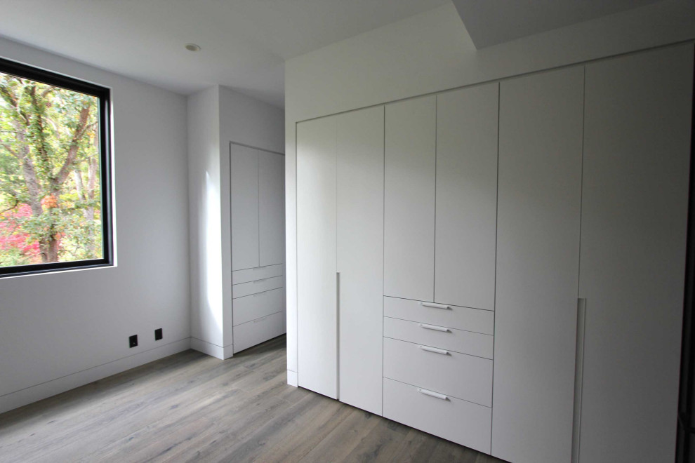 Imagen de armario unisex moderno de tamaño medio con armarios con paneles lisos, puertas de armario blancas, suelo de madera clara y suelo gris