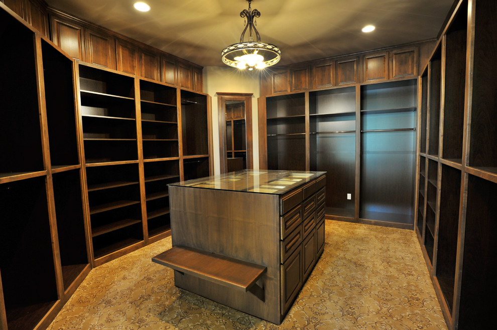 Large mediterranean gender neutral walk-in wardrobe in Sacramento with open cabinets, dark wood cabinets and carpet.