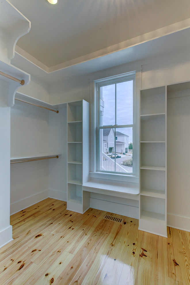 Modelo de armario vestidor unisex campestre de tamaño medio con armarios abiertos, puertas de armario blancas y suelo de madera clara