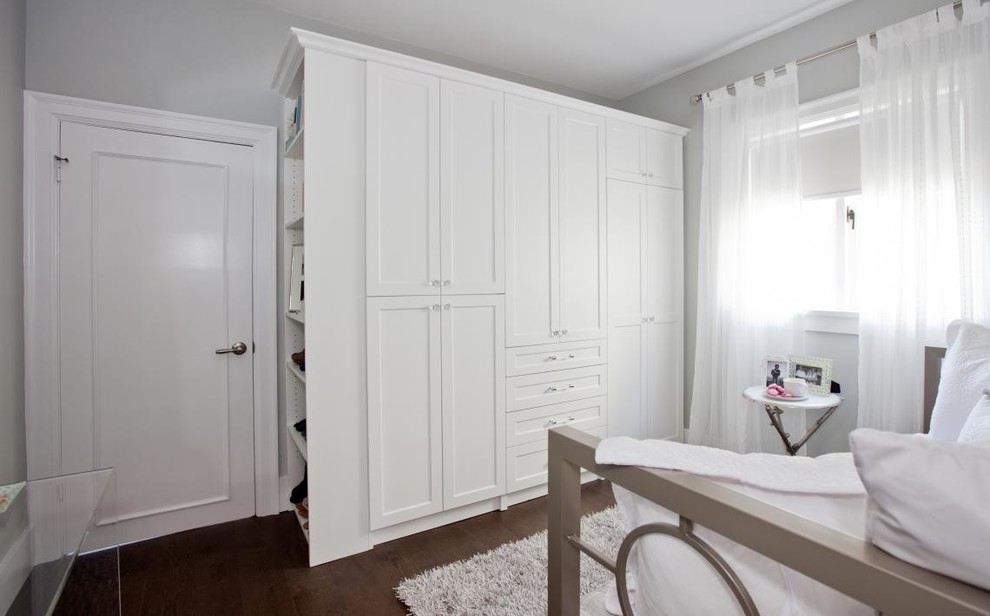 This is an example of a large classic walk-in wardrobe for women in Vancouver with recessed-panel cabinets, white cabinets and medium hardwood flooring.