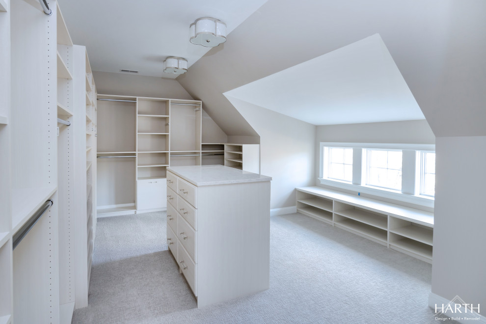 This is an example of a large classic walk-in wardrobe for women in Philadelphia with flat-panel cabinets, light wood cabinets, carpet and beige floors.