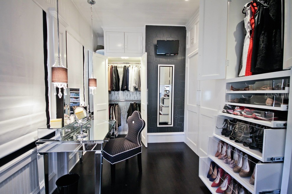 This is an example of a traditional dressing room for women in Austin with glass-front cabinets, white cabinets and dark hardwood flooring.