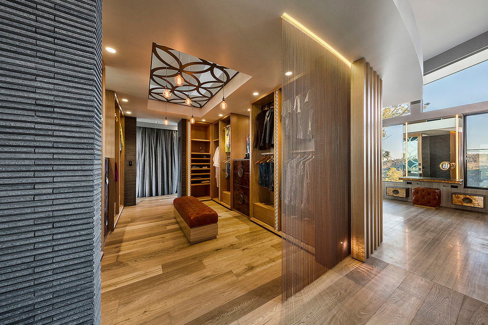 Idée de décoration pour un très grand dressing room design neutre avec un sol en bois brun et des rideaux.