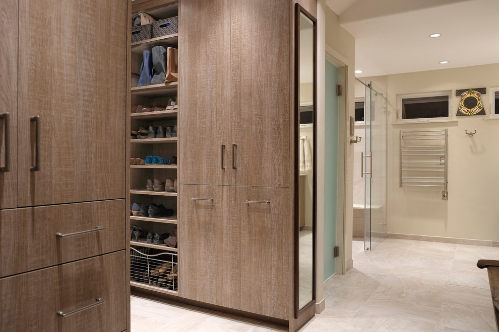 Modelo de armario vestidor unisex contemporáneo con armarios con paneles lisos, puertas de armario de madera clara, suelo de baldosas de porcelana y suelo beige