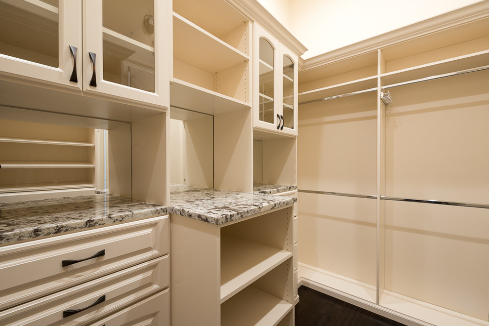 Large traditional walk-in wardrobe for women in Orlando with raised-panel cabinets, white cabinets and dark hardwood flooring.