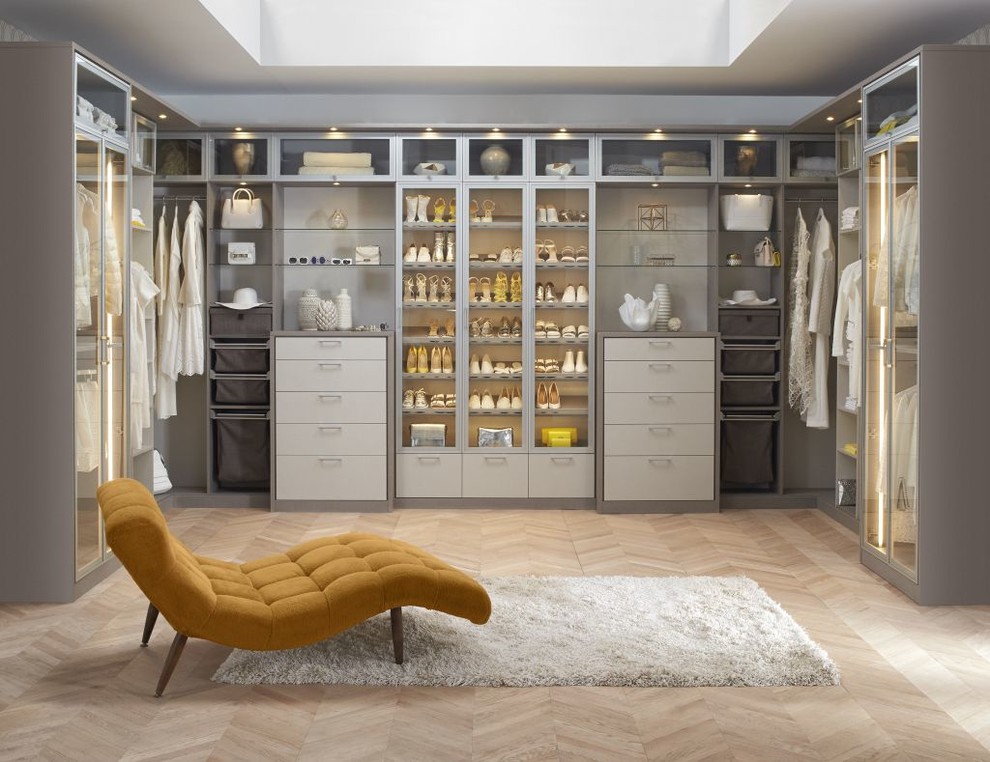 Modelo de vestidor unisex minimalista grande con armarios con paneles lisos, puertas de armario blancas, suelo de madera clara y suelo beige