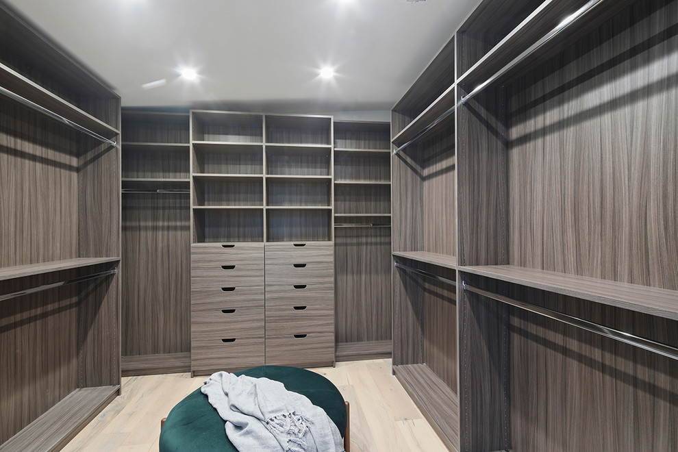 Diseño de armario vestidor unisex minimalista grande con armarios con paneles lisos, puertas de armario de madera oscura, suelo de madera clara y suelo beige