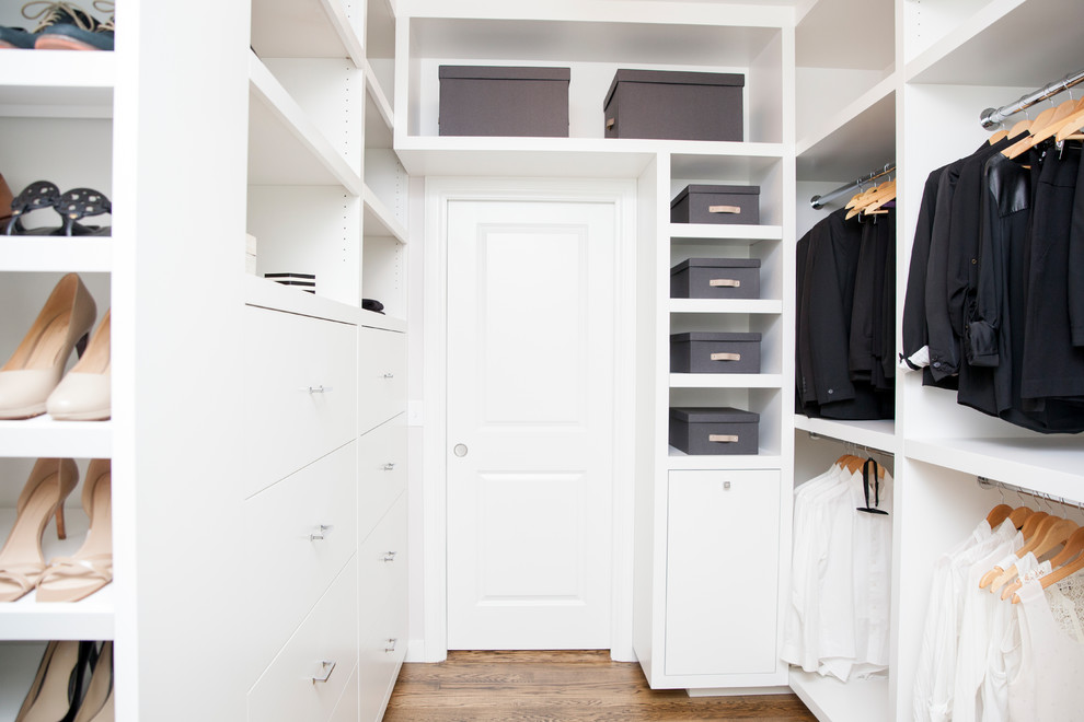 Ejemplo de armario vestidor unisex clásico renovado de tamaño medio con armarios con paneles lisos, puertas de armario blancas, suelo de madera oscura y suelo marrón