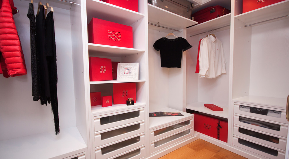 Imagen de armario vestidor de mujer clásico pequeño con armarios abiertos, puertas de armario blancas y suelo de madera en tonos medios