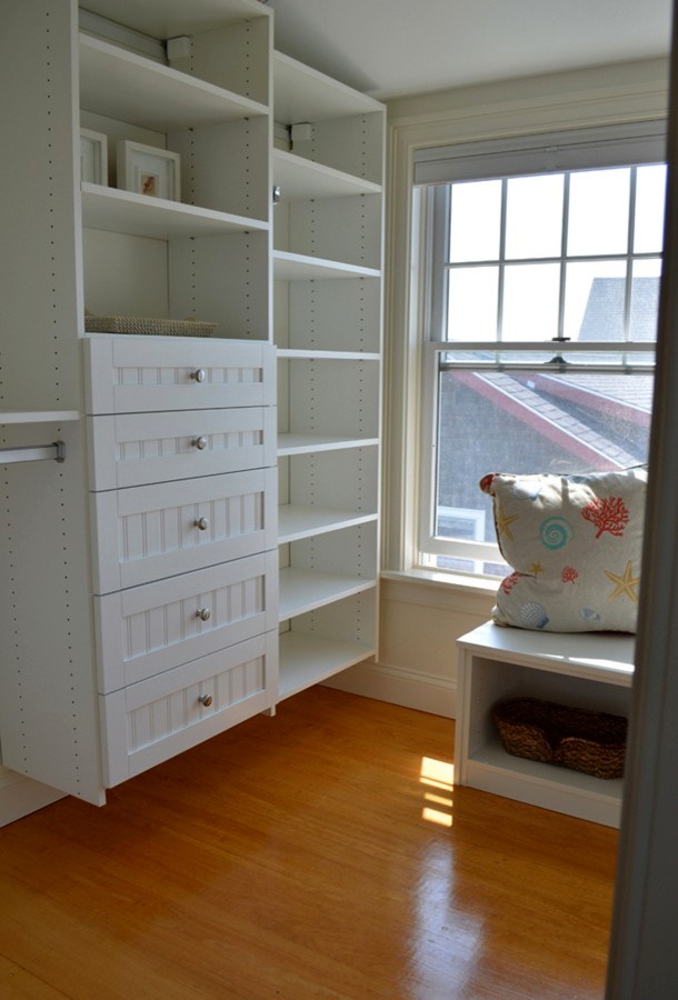 Inspiration for a small coastal gender neutral walk-in wardrobe in Portland Maine with recessed-panel cabinets, white cabinets and medium hardwood flooring.