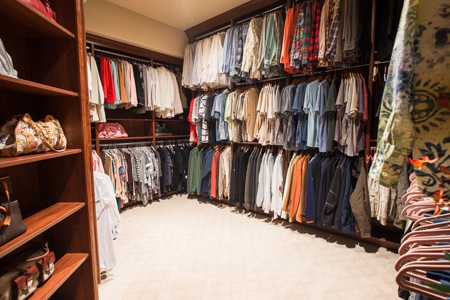 This is an example of a large gender neutral walk-in wardrobe in Las Vegas with dark wood cabinets and carpet.