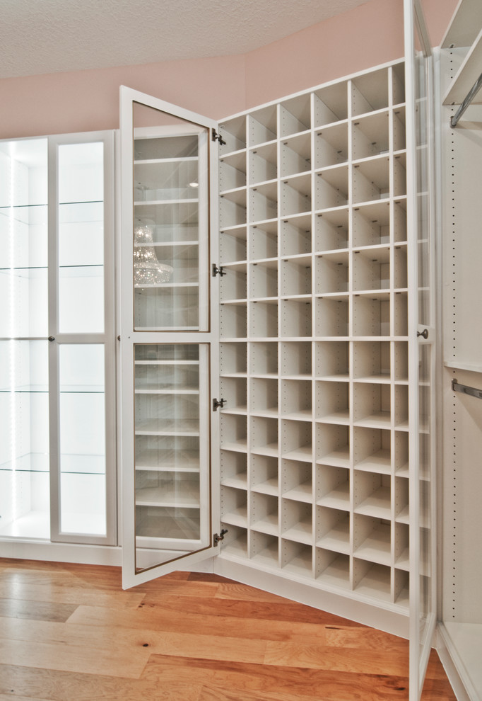 Idee per una grande cabina armadio unisex tradizionale con ante di vetro, ante bianche e pavimento in legno massello medio