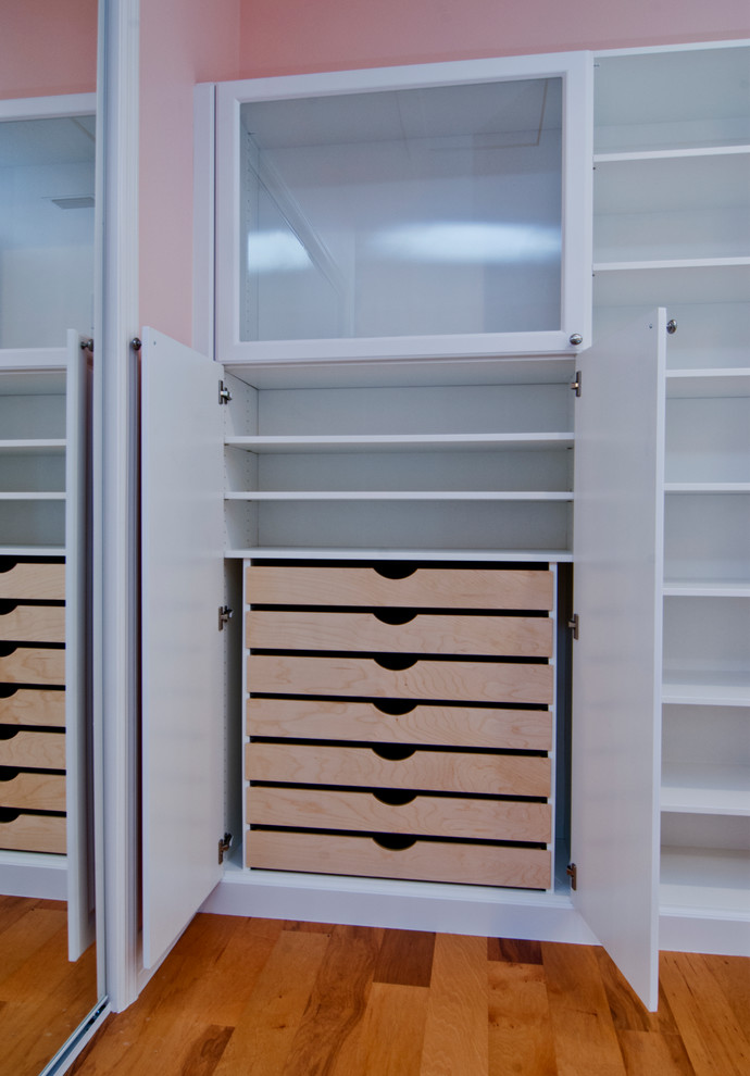 Diseño de armario vestidor unisex clásico grande con puertas de armario blancas y suelo de madera en tonos medios