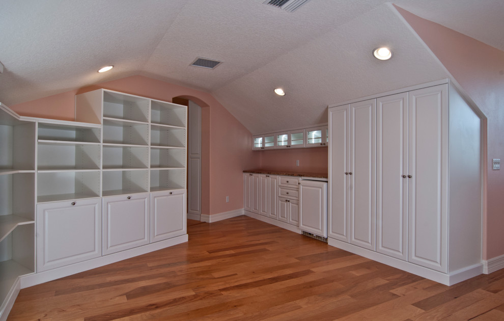 Inspiration for a large timeless gender-neutral medium tone wood floor walk-in closet remodel in Orlando with raised-panel cabinets and white cabinets
