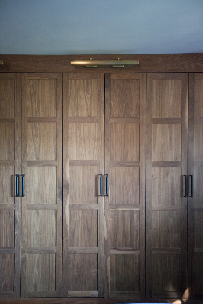 Ejemplo de armario unisex contemporáneo de tamaño medio con armarios con paneles empotrados y puertas de armario de madera oscura