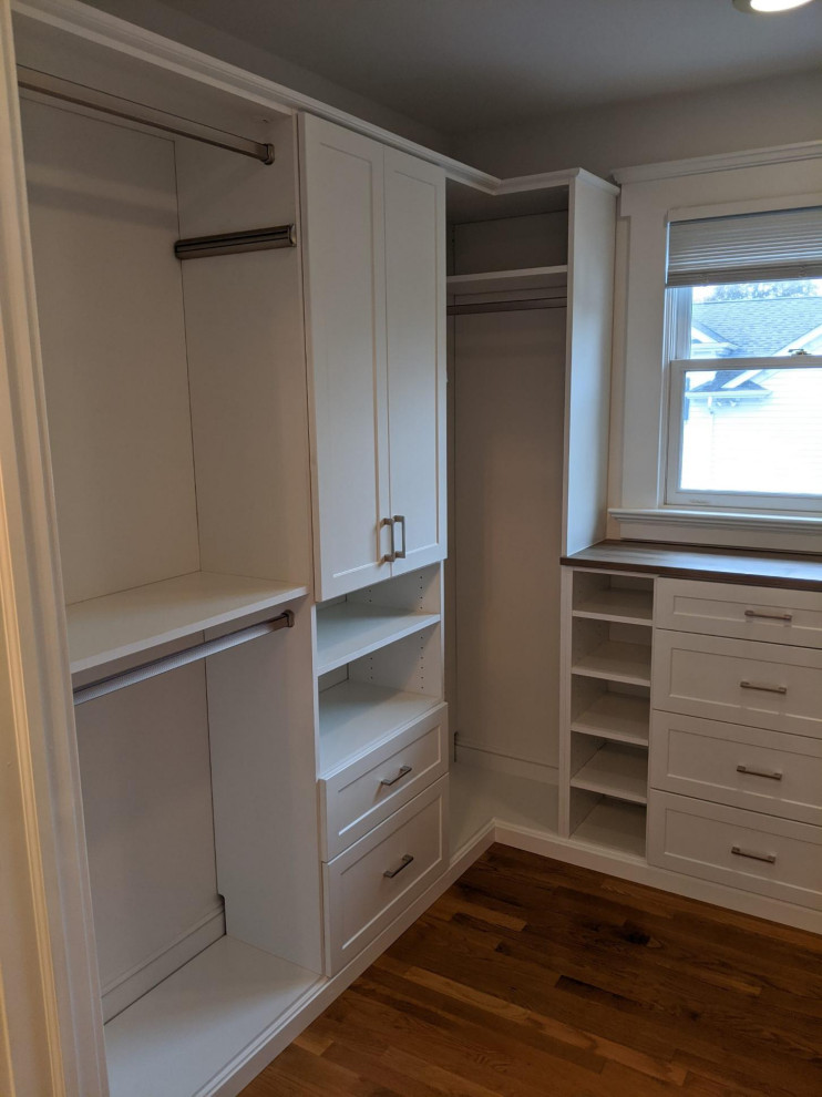 Photo of a medium sized traditional gender neutral built-in wardrobe in New York with recessed-panel cabinets, white cabinets, dark hardwood flooring and brown floors.