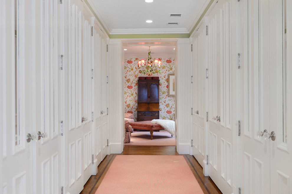 Geräumiges Klassisches Ankleidezimmer mit weißen Schränken und braunem Holzboden in New York