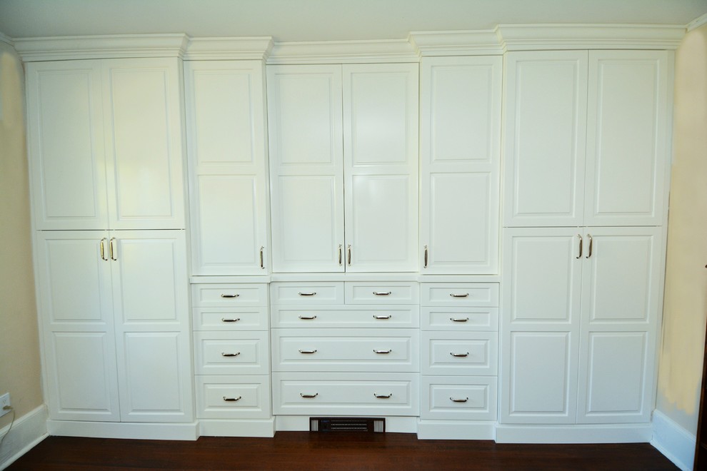 Foto de armario unisex clásico de tamaño medio con armarios con paneles con relieve, puertas de armario blancas y suelo de madera oscura