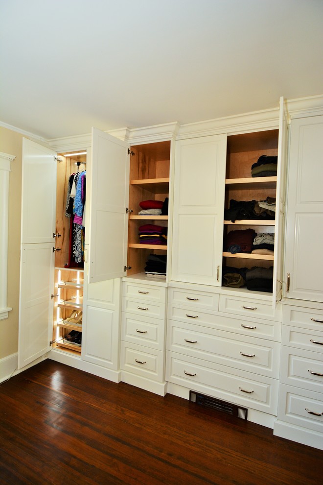 Foto de armario unisex tradicional con armarios con paneles con relieve, puertas de armario blancas y suelo de madera oscura