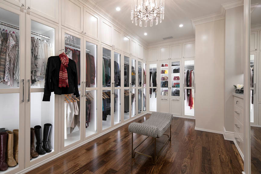 Ejemplo de armario vestidor unisex clásico extra grande con puertas de armario blancas y suelo de madera en tonos medios