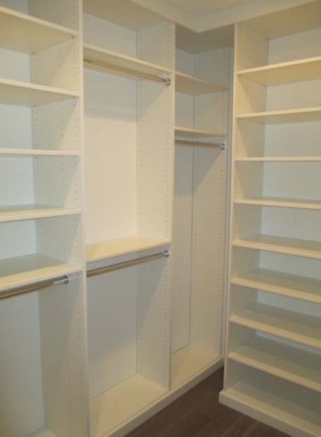 Walk-in closet - mid-sized contemporary gender-neutral medium tone wood floor and brown floor walk-in closet idea in Los Angeles with flat-panel cabinets and white cabinets