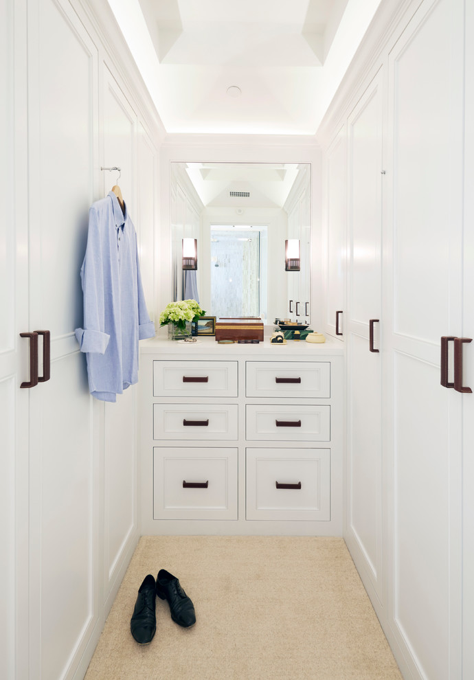 Diseño de armario vestidor unisex clásico renovado con armarios con paneles empotrados, puertas de armario blancas y suelo beige