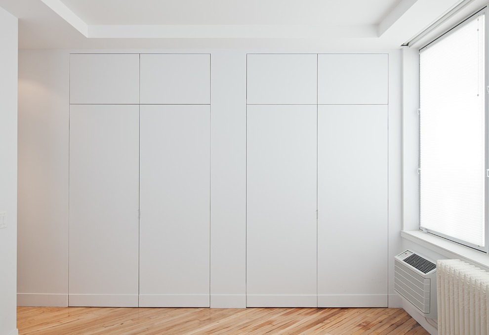 Cette photo montre un placard dressing tendance avec un placard à porte plane et des portes de placard blanches.