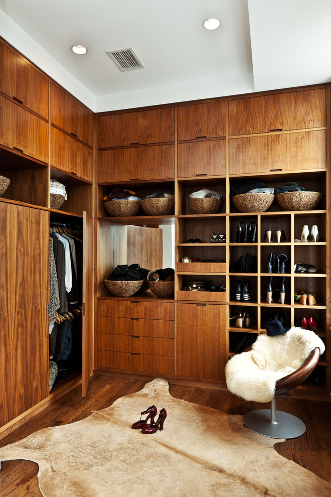 Modelo de armario y vestidor unisex contemporáneo con armarios con paneles lisos, puertas de armario de madera en tonos medios y suelo de madera oscura