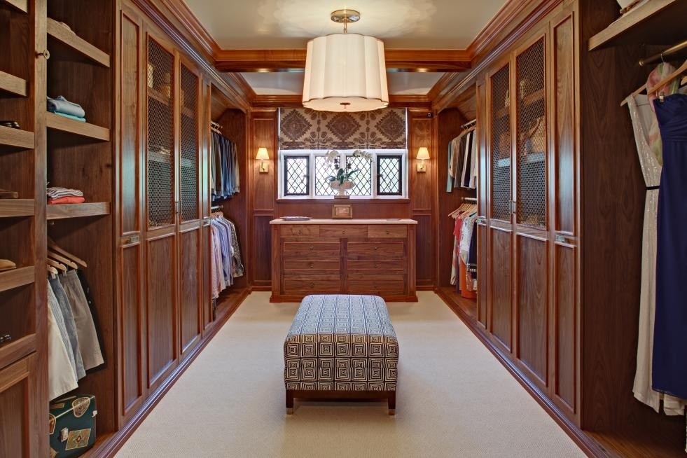 На фото: большая гардеробная комната унисекс в классическом стиле с фасадами с утопленной филенкой, ковровым покрытием и фасадами цвета дерева среднего тона с