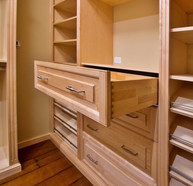 Diseño de armario vestidor clásico de tamaño medio con armarios con paneles con relieve, puertas de armario de madera clara y suelo de madera oscura