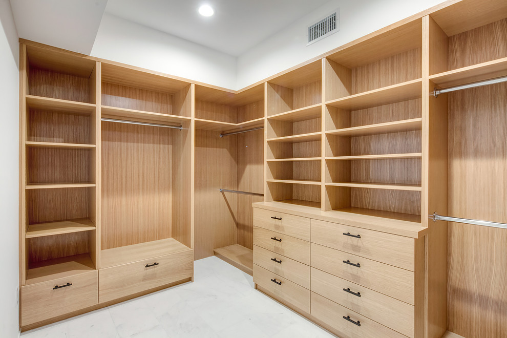 Photo of a medium sized modern gender neutral walk-in wardrobe in Los Angeles with flat-panel cabinets, light wood cabinets, marble flooring and white floors.
