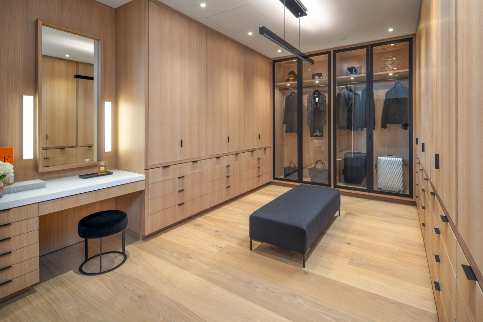 Modernes Ankleidezimmer mit Ankleidebereich, flächenbündigen Schrankfronten, hellen Holzschränken, hellem Holzboden und beigem Boden in Orange County