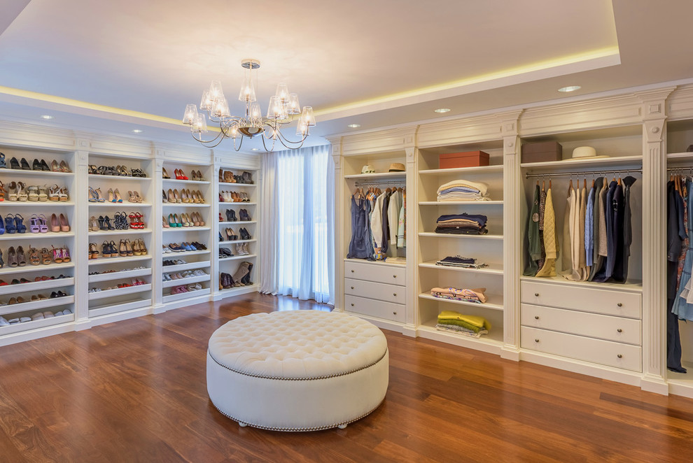 Diseño de armario vestidor de mujer clásico extra grande con armarios abiertos, puertas de armario blancas, suelo marrón y suelo de madera en tonos medios
