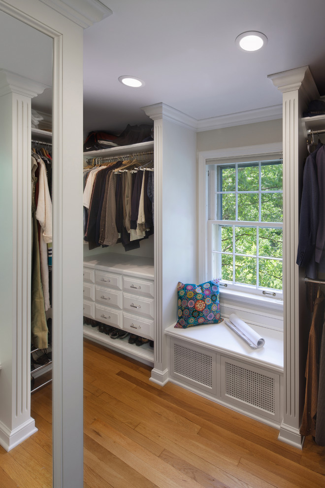 Diseño de armario vestidor clásico grande con armarios con paneles con relieve, puertas de armario blancas y suelo de madera en tonos medios