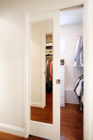 Foto de armario vestidor de hombre clásico de tamaño medio con suelo de madera oscura, armarios con paneles lisos, puertas de armario blancas y suelo marrón