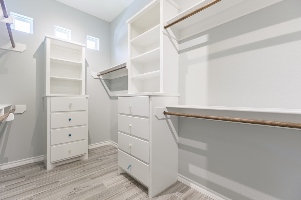 Inspiration for a mid-sized coastal gender-neutral porcelain tile walk-in closet remodel in Austin with flat-panel cabinets and white cabinets