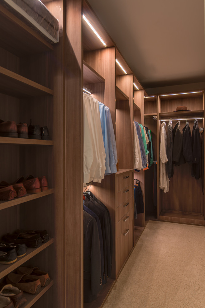 Modelo de armario vestidor de hombre contemporáneo de tamaño medio con armarios abiertos, puertas de armario de madera oscura, moqueta y suelo beige