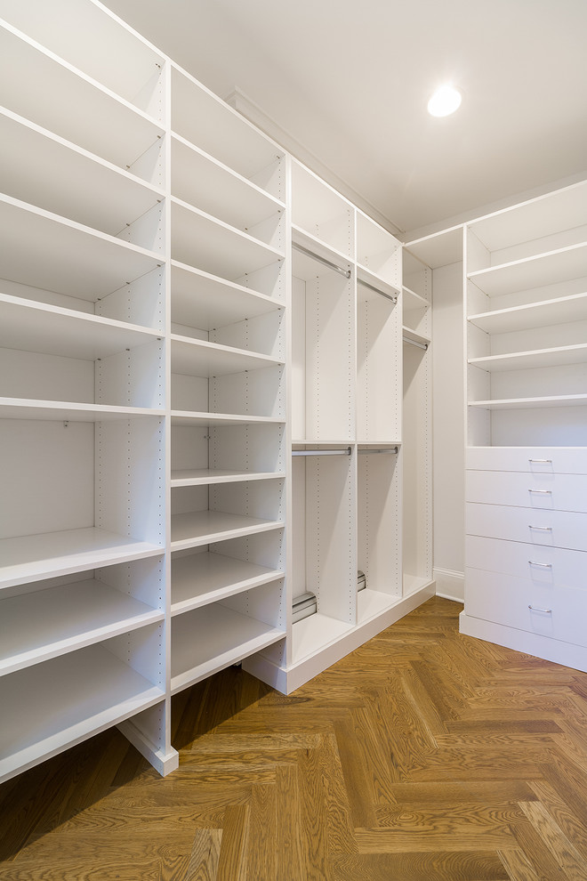 Foto de armario vestidor unisex tradicional renovado pequeño con armarios con paneles lisos, puertas de armario blancas, suelo de madera en tonos medios y suelo marrón