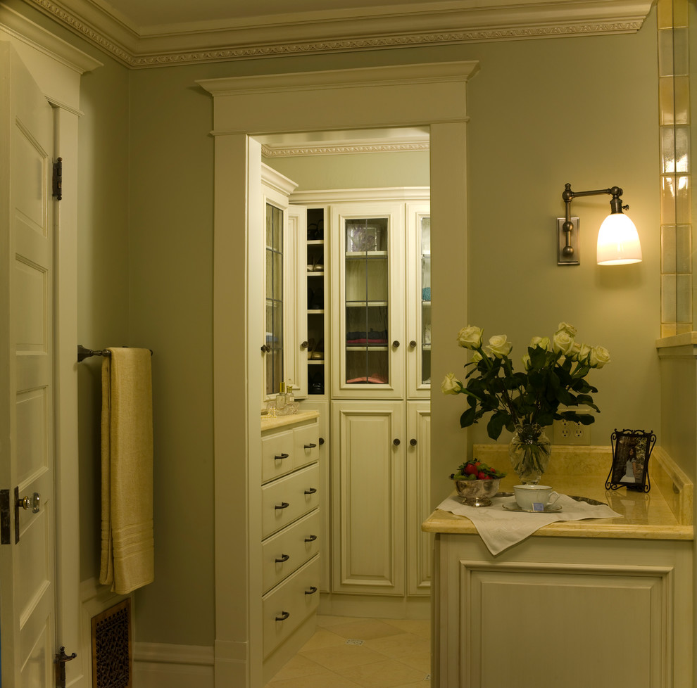 This is an example of a small traditional walk-in wardrobe for women in Denver with white cabinets and travertine flooring.