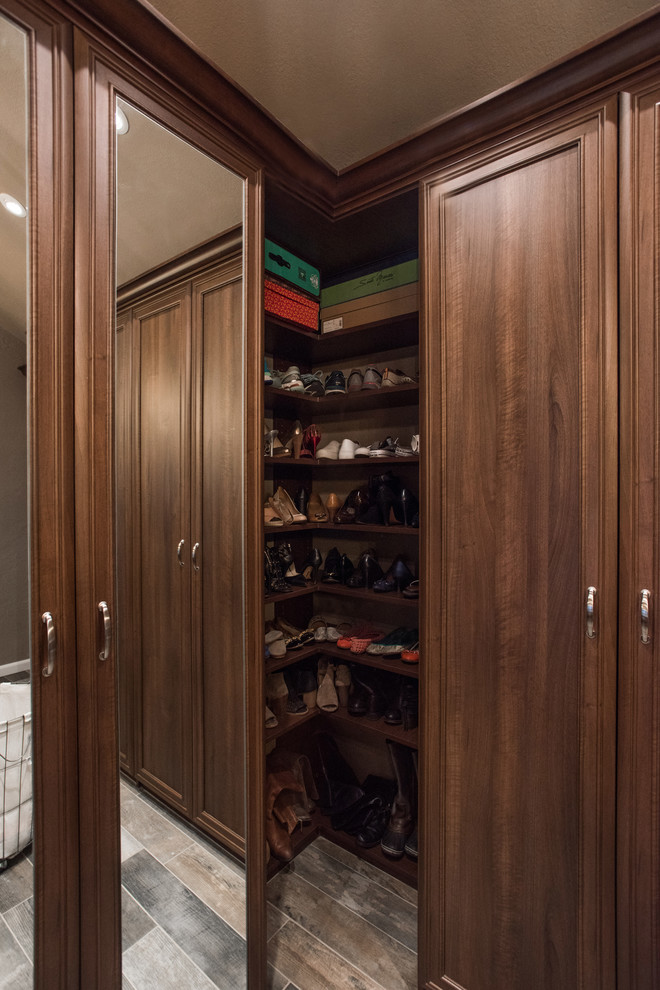 Modelo de armario vestidor tradicional renovado grande con armarios con paneles empotrados, puertas de armario de madera oscura, suelo de piedra caliza y suelo gris
