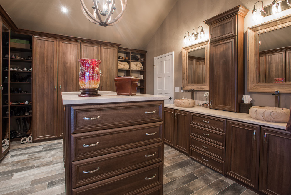 Example of a large transitional limestone floor and gray floor walk-in closet design in Denver with recessed-panel cabinets and medium tone wood cabinets