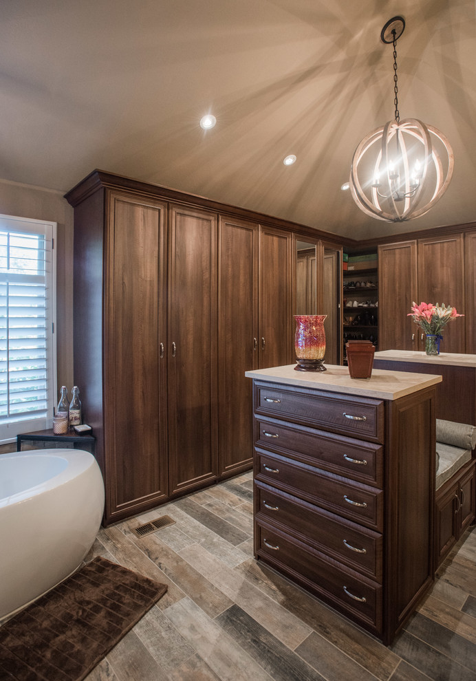 Inspiration for a large transitional limestone floor and gray floor walk-in closet remodel in Denver with recessed-panel cabinets and medium tone wood cabinets