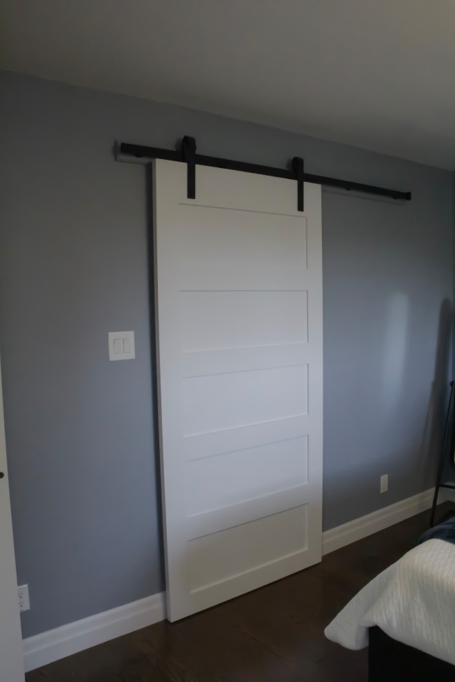 Diseño de armario vestidor unisex de tamaño medio con puertas de armario blancas, suelo de madera oscura y suelo marrón