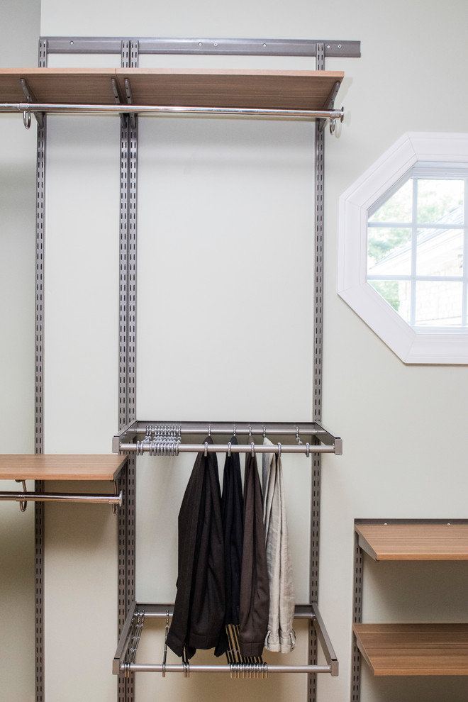 Diseño de armario vestidor unisex minimalista extra grande con armarios con paneles lisos, puertas de armario de madera oscura, suelo de madera en tonos medios y suelo marrón
