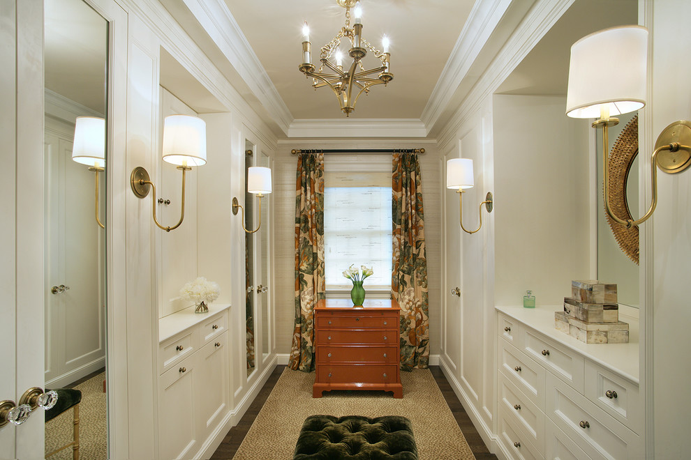 This is an example of a large traditional dressing room for women in New York with recessed-panel cabinets, white cabinets, dark hardwood flooring and brown floors.