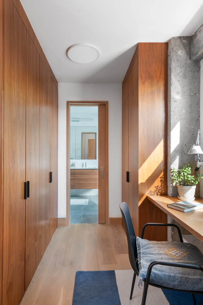 Modernes Ankleidezimmer mit hellem Holzboden, beigem Boden, Ankleidebereich, flächenbündigen Schrankfronten und hellbraunen Holzschränken in New York