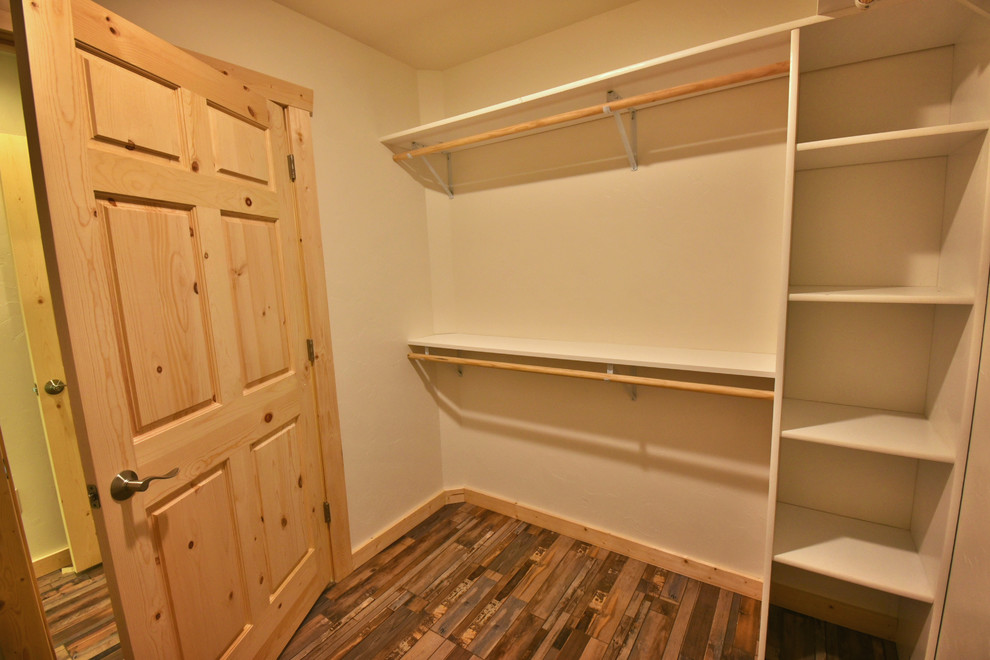 Foto de armario vestidor unisex rural de tamaño medio con armarios abiertos, puertas de armario blancas, suelo de madera en tonos medios y suelo marrón