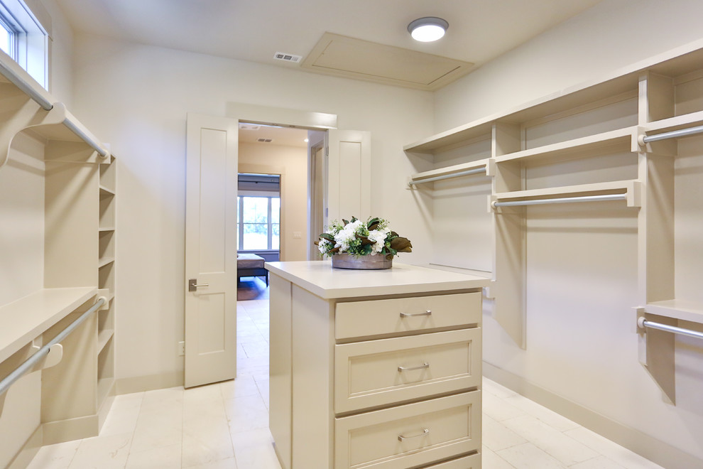 Example of a huge classic gender-neutral ceramic tile and white floor walk-in closet design in Austin with recessed-panel cabinets and beige cabinets