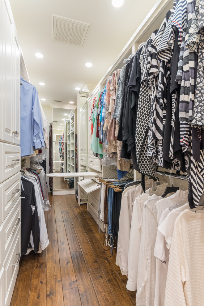 Diseño de armario vestidor unisex tradicional renovado de tamaño medio con armarios con paneles con relieve, puertas de armario blancas y suelo de madera en tonos medios