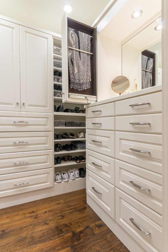 Ejemplo de armario vestidor unisex clásico grande con armarios con paneles con relieve, puertas de armario blancas y suelo de madera en tonos medios